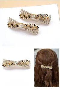 Macro detail of alloy bow hair clip with sparkling rhinestones and black flower accents