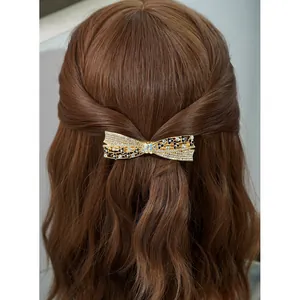 Elegant large bow hair clip with sparkling rhinestones on long brown wavy hair