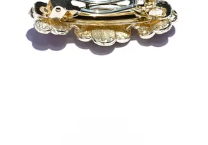 Detail view of the golden metal spring clip mechanism and floral hair clip structure