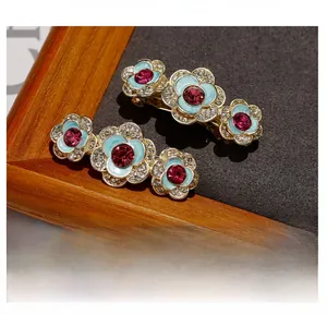 Detail of floral hair clip with blue enamel petals and purple crystals on gold alloy base