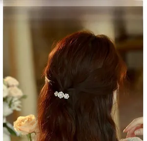Detail of three-petal rose hair clip in celadon enamel with pink crystal accents