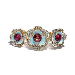 Gold hair clip with pink gems and blue enamel flowers with crystals on white background