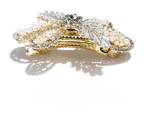 Detailed macro view of luxury gold-plated bow hair clip with crystal zircons and white pearls