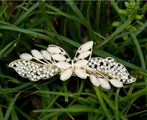 Detailansicht der goldener Schmetterlings-Haarspange mit Katzenaugensteinen auf Gras