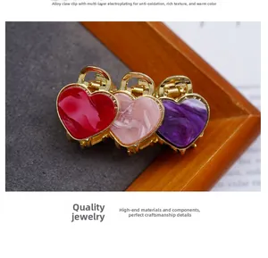 Detail of heart-shaped acetate hair claw clips with marble texture and gold alloy frame