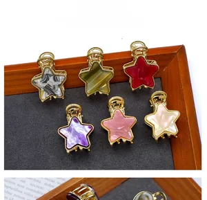 Star-shaped acetate hair claws in marble patterns with golden metal clips on a display board