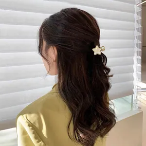 Star-shaped cream acetate hair claw clip with gold edging shown on long brown hair