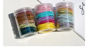 Detailed view of colorful high-elastic hair ties in three transparent plastic bottles
