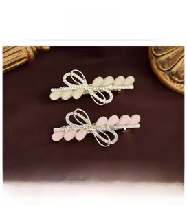 Détail de la barrette nœud avec strass et perles gouttes en crème et rose poudré