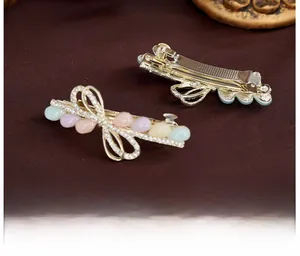 Vue détaillée d'une barrette noeud dorée avec perles en résine colorées et strass