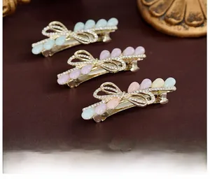 Détail de barrettes à strass en forme de nœud avec alliage or rose et résine colorée