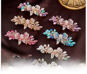 Macro detail of six crystal bow hair clips in various colors on brown silk fabric