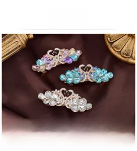 Detailed view of swan-shaped hair clips with sparkling crystals in three vibrant colors