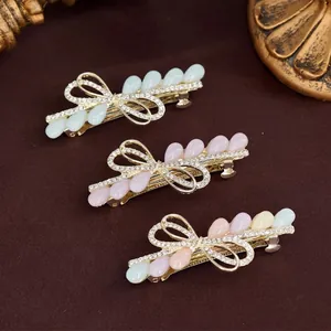 Trois barrettes à nœuds élégantes avec cristaux et perles sur un fond en velours marron