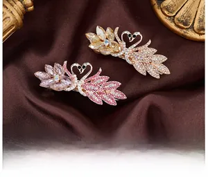 Macro detail of swan hair clips with pink crystals on rose gold metal and silk background