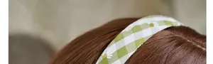 Detail eines grünen Gingham-Haarband mit Gänseblümchen-Muster aus weichem Stoff