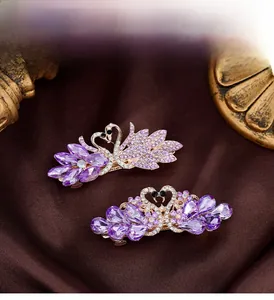Detail of luxury swan hair clips with purple crystals on a vintage velvet background