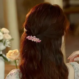 Elegant floral hair clip with pink crystals on dark wavy hair for autumn fashion style