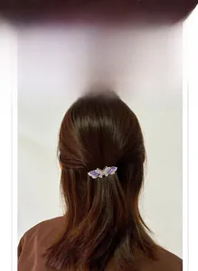 Details einer kleinen Schmetterlings-Haarklammer mit lila Steinen und Kristallen