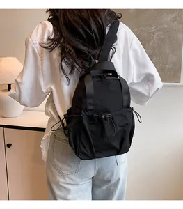 Detail of black pleated nylon backpack featuring side drawstring pocket and durable strap