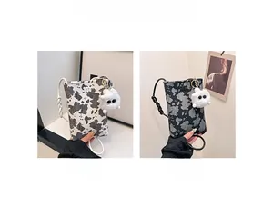 Cow print crossbody phone bag in black and white with cute plush monster charm