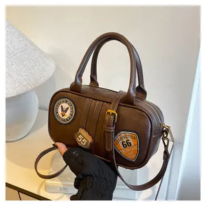 Detail of dark brown leather Boston bag featuring vintage American embroidery patches