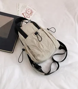 Detailed view of beige nylon crossbody bag with adjustable strap and drawstring pocket