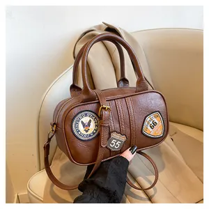 Close-up of vintage brown Boston bag with US Navy embroidery patches on a cream sofa