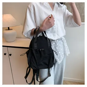 Detail of minimalist black nylon backpack featuring functional drawstring pocket design
