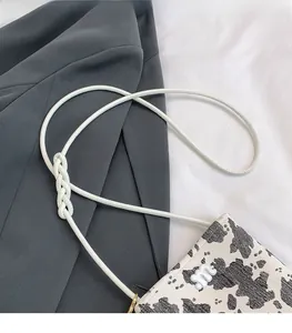 Detail of the spotted crossbody bag showing cow print texture and knotted rope strap