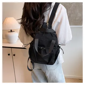 Minimalist black nylon backpack shown on model in a modern interior setting
