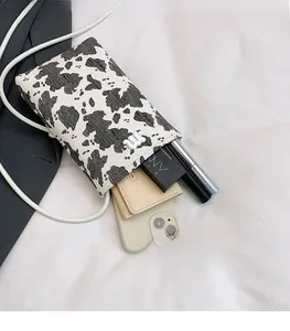 Detailed interior view of cow print mini bag showing storage for phone and cosmetics