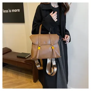 Detail of a brown leather backpack showing pebble texture and gold buckle closure