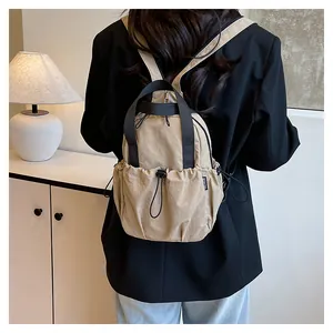 Detail of khaki nylon backpack with fashion tag, adjustable straps and drawstring closure