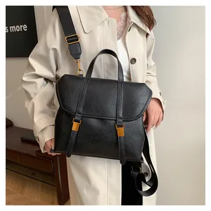 Detail of vintage black leather handbag with gold metal buckles and wide textile strap