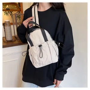 Close-up of cream nylon backpack featuring drawstring pockets and black adjustable strap