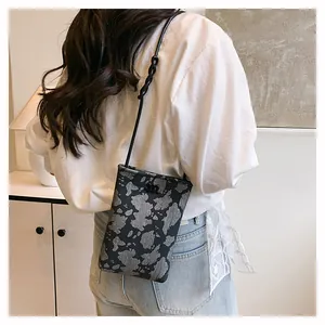 Detail of a mini crossbody bag with black jacquard cow print and metal letter M logo
