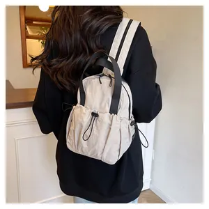 Detailed close-up of cream nylon backpack with adjustable drawstring and black straps