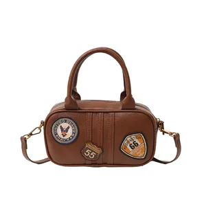 Vintage brown Boston bag with embroidered badges and top handles for casual styling