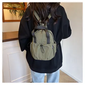 Detail of army green nylon backpack showing pleated fabric and fashion woven label