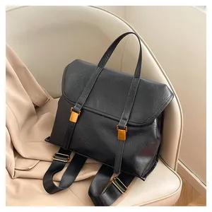 Detail of vintage black leather backpack with gold buckles on a beige chair
