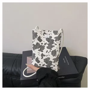 Close-up of stylish black and white cow print mobile phone bag with a metal 'm' logo