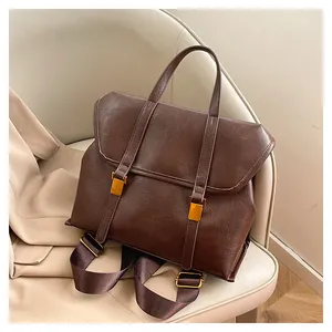 Detail of vintage brown leather backpack with golden buckles and textured flap cover