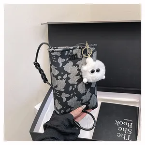 Detail of trendy phone bag with m-logo hardware and a white fuzzy monster charm