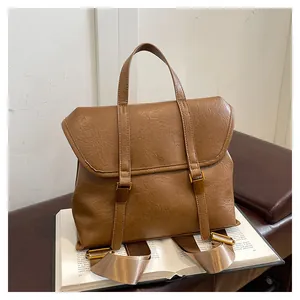 Close-up of vintage brown leather bag on books showing metal buckle and texture