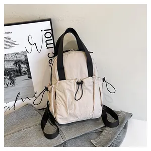Close-up of beige nylon backpack featuring drawstring pockets and black webbing straps