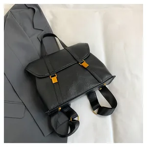 Detail of black textured leather backpack with gold buckles on grey blazer background