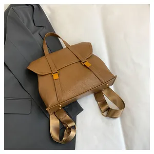 Detail of caramel brown backpack with pleated texture and golden buckle on gray blazer