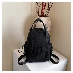 Detail of minimalist black nylon backpack with drawstring pockets in a zen setting