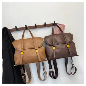 Detailed view of brown PU leather vintage backpacks featuring gold metal buckles and flaps